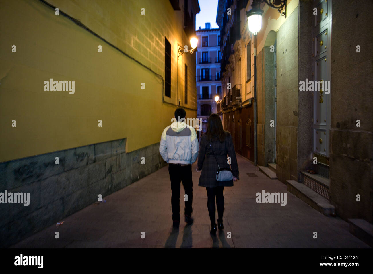 Un giovane uomo e donna camminare insieme dopo aver goduto di un lungo party night out a Madrid, Spagna. Foto Stock