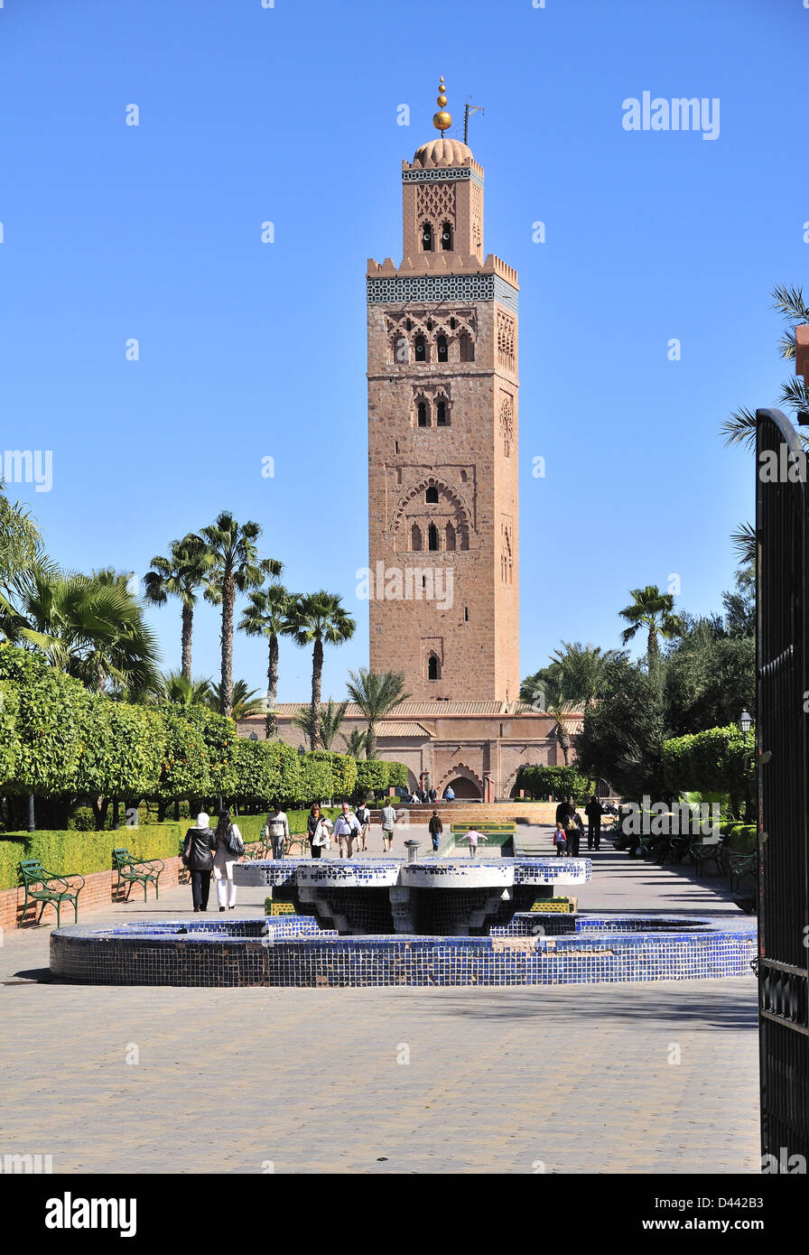Minareto della Moschea di Koutoubia con persone a piedi attraverso i giardini di Koutoubia, Marrakech (Marrakech) Marocco Foto Stock