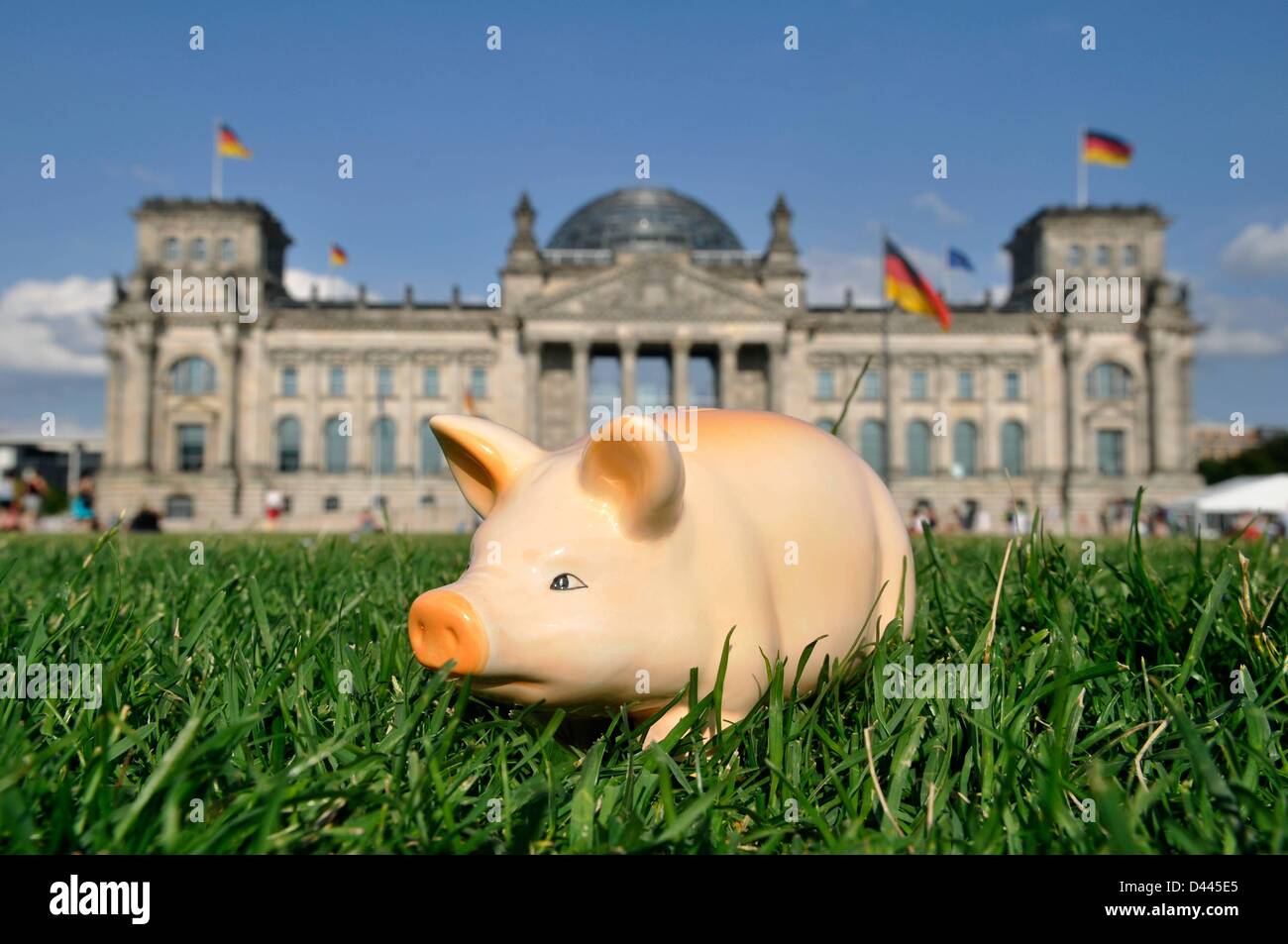 Illustrazione - Una banca del piggy è rappresentata in piedi sul prato davanti al Reichstag tedesco a Berlino, tedesco, 10 luglio 2011. Fotoarchiv für ZeitgeschichteS.Steinach Foto Stock