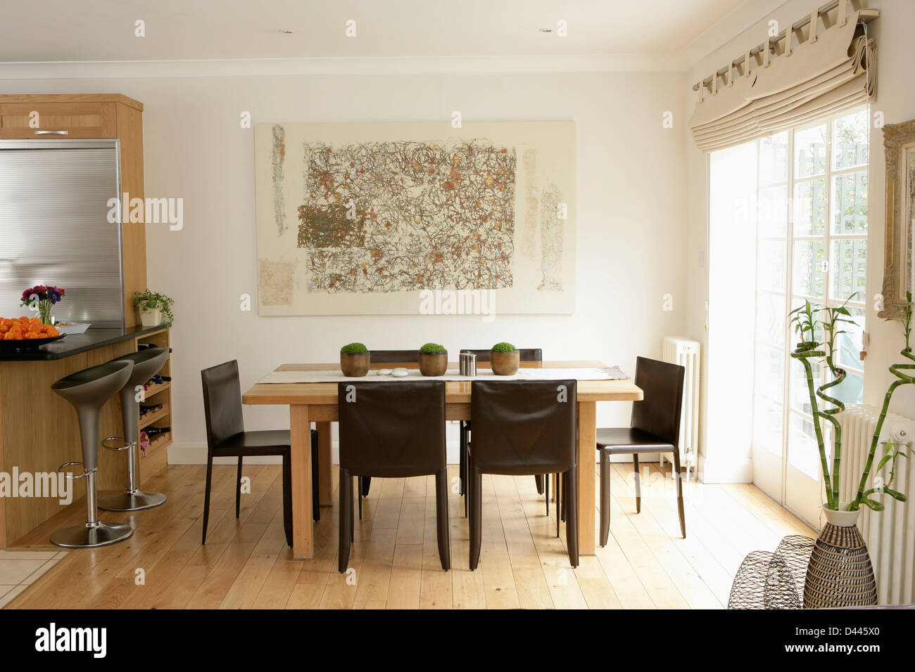 Nero e sedie di legno pallido tavola nella sala da pranzo della moderna cucina bianca con il pavimento in legno Foto Stock