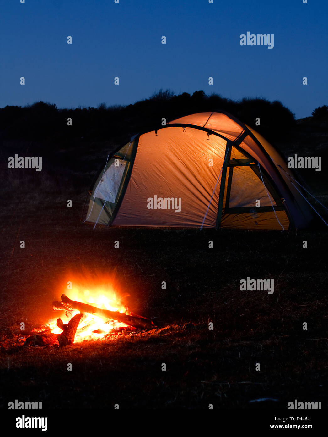 Tenda si illumina di notte con il fuoco davanti che simboleggiano vacanza in campeggio o in vacanza nel paese Foto Stock