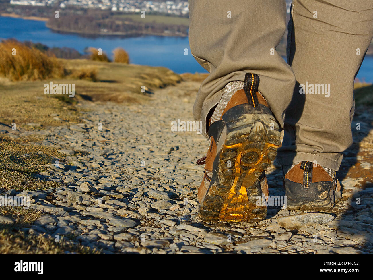 Walker per giorni di trekking nel distretto del lago con close up sulle calzature per uso esterno e il paesaggio di sfondo Foto Stock