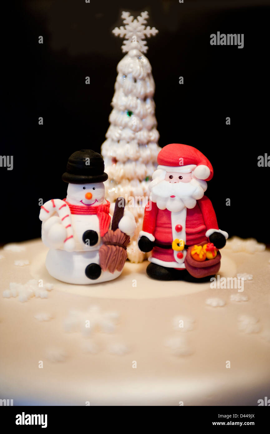 Verticale di chiusura del divertimento modellato figure di Babbo Natale e un pupazzo di neve in piedi su una torta di Natale. Foto Stock