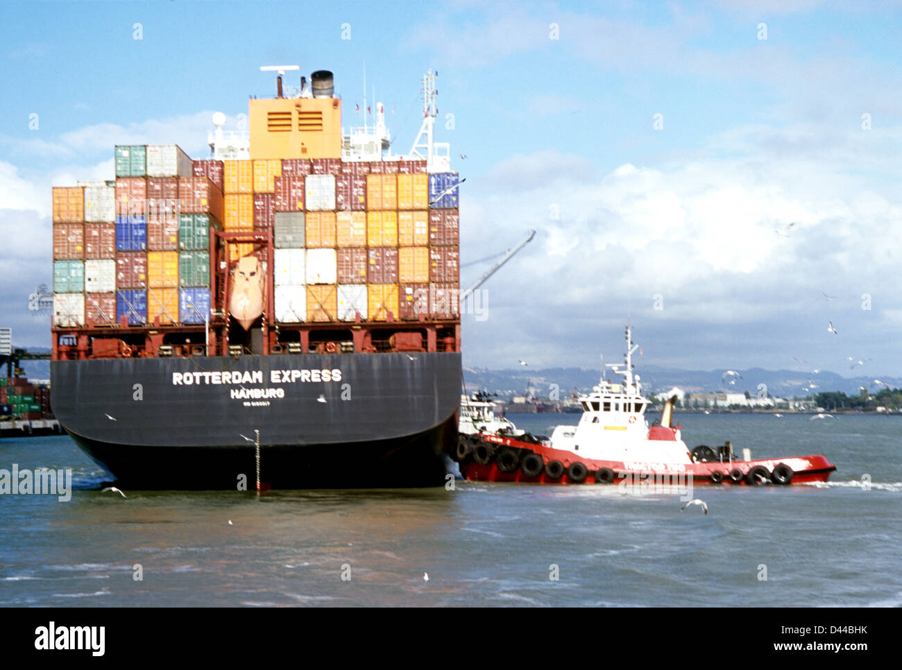 Contenitore tedesco nave ormeggia con l aiuto del rimorchiatore a terminale di Oakland Foto Stock