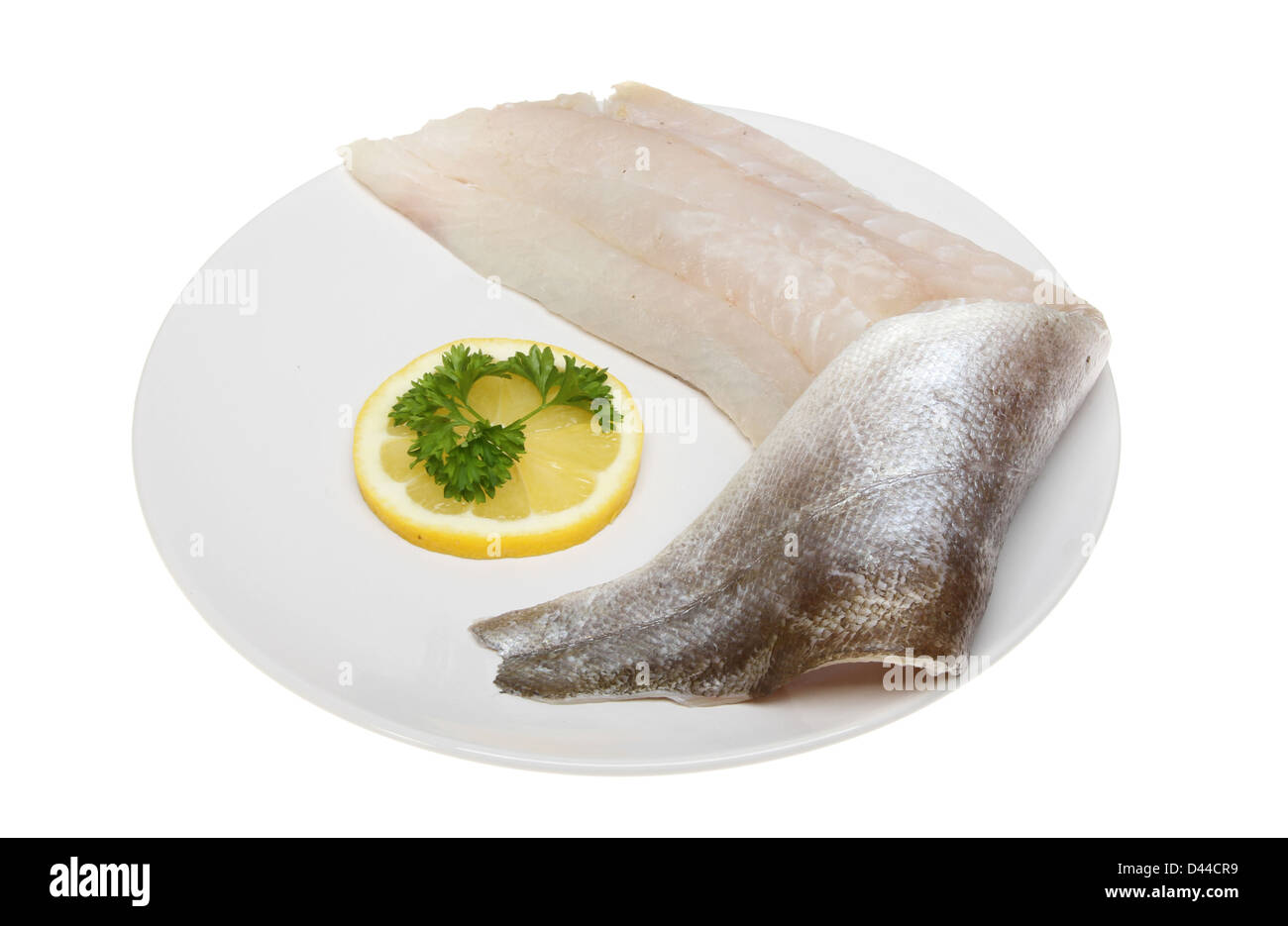 Materie pollock filetto di pesce su una piastra con limone e prezzemolo isolata contro bianco Foto Stock