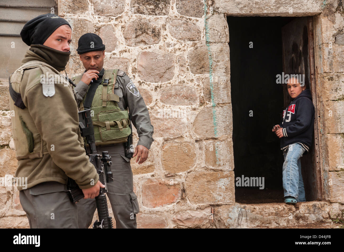 Hebron, Cisgiordania, Israele. Una ragazza palestinese guarda a due guardie di frontiera israeliana. Foto Stock