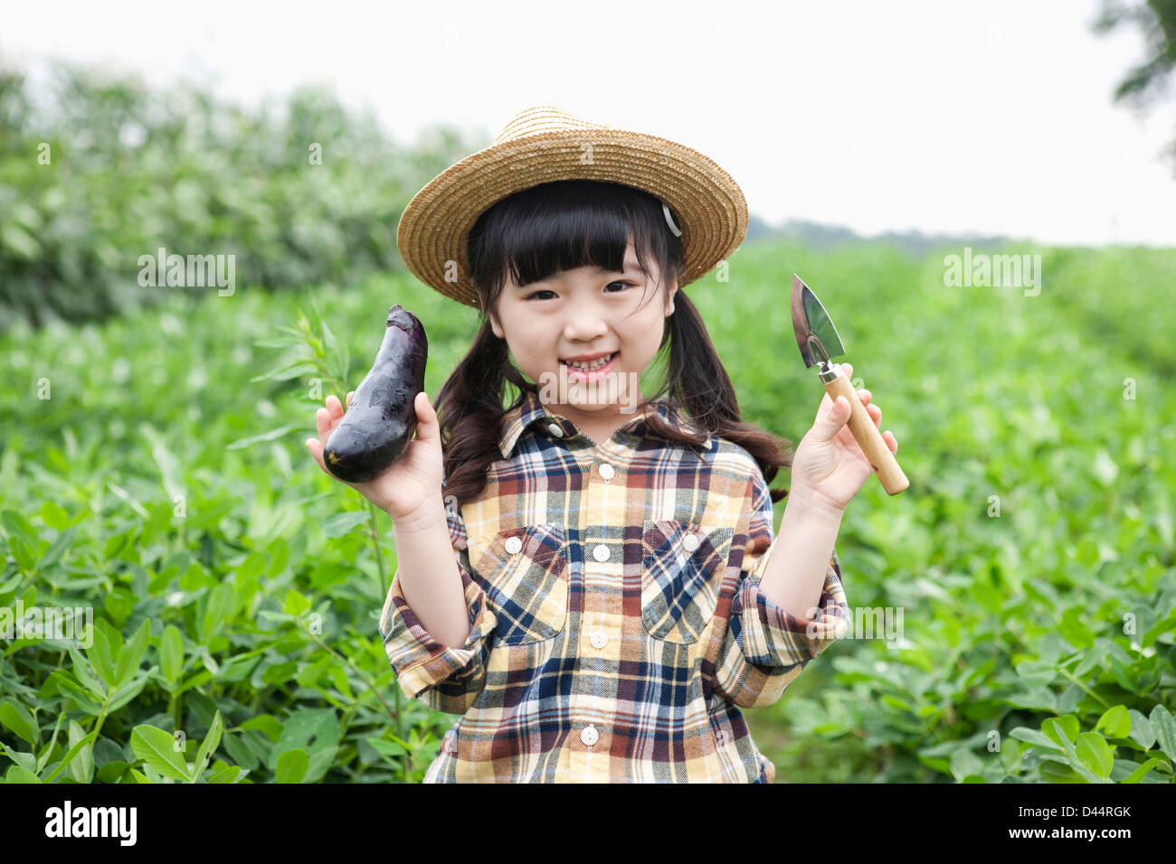 Una ragazza in dell'agricoltore hat in posa con le melanzane Foto Stock