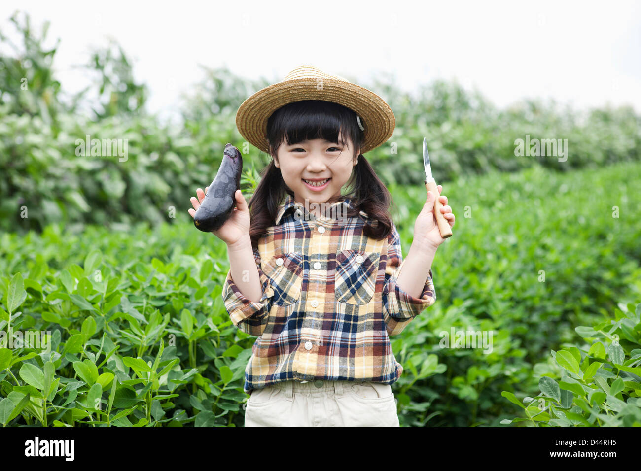 Una ragazza in dell'agricoltore hat in posa con le melanzane Foto Stock