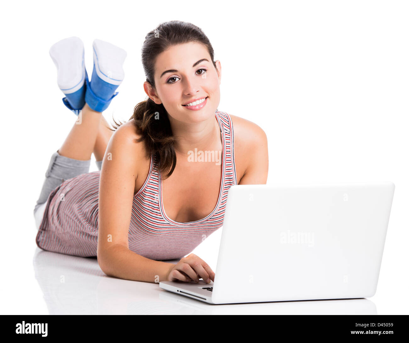 Bella studente giacente nel piano lavoro in un computer portatile, isolato su uno sfondo bianco Foto Stock