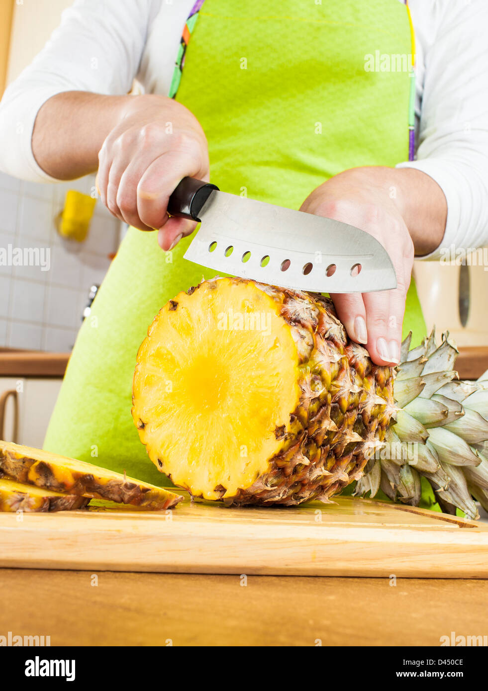 Donna con le mani in mano il taglio di ananas fresco su cucina Foto Stock