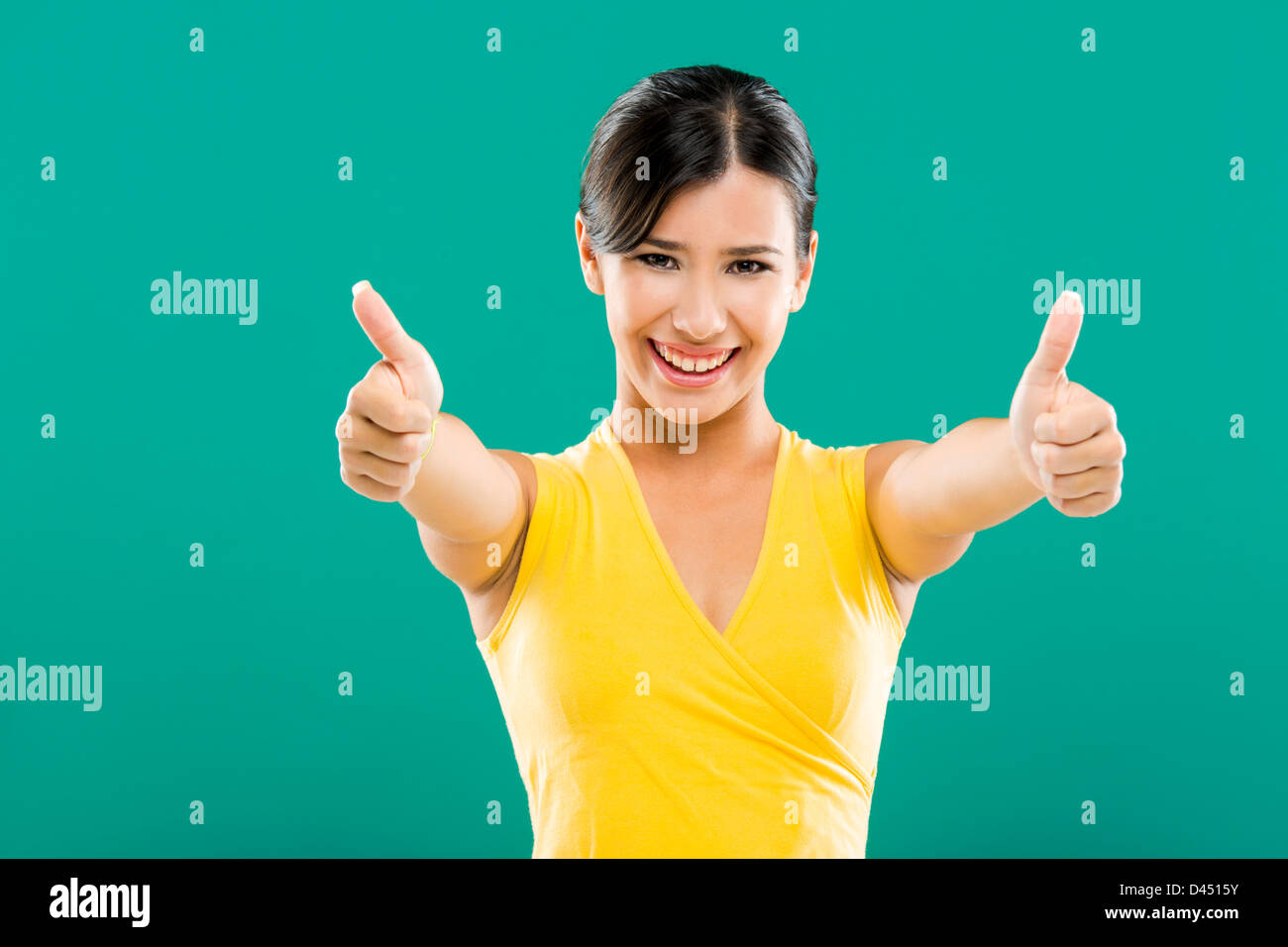 Bella e felice donna asiatica con il pollice in alto, su uno sfondo verde Foto Stock