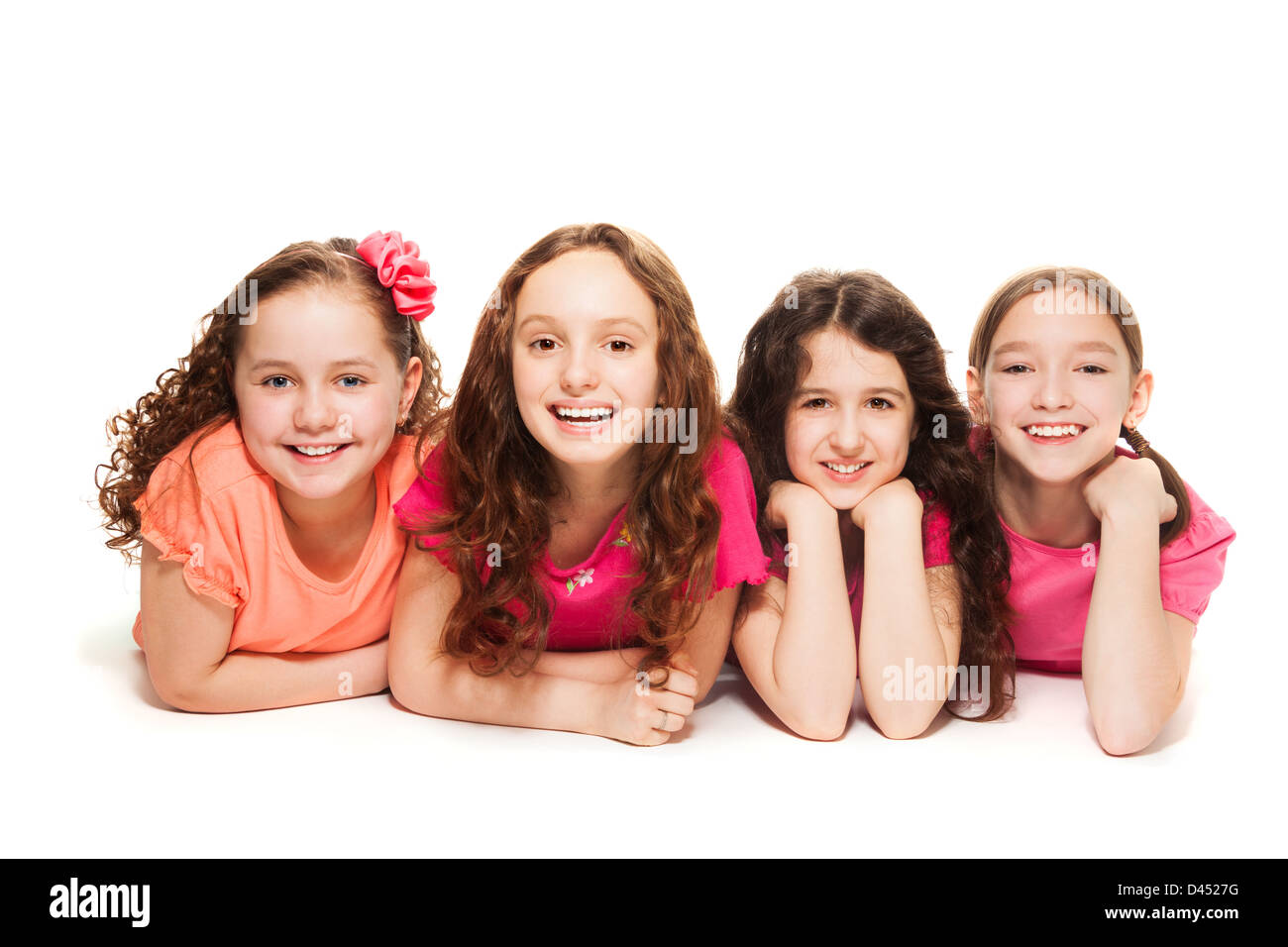 Quattro felice incredibile 10 anni le ragazze in rosa la posa sul pavimento, isolato su bianco Foto Stock