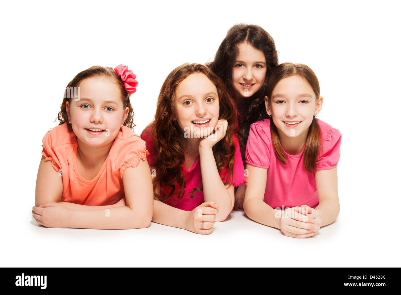 Felice in età scolare le ragazze la posa sul pavimento insieme in maglia rosa, isolato su bianco Foto Stock