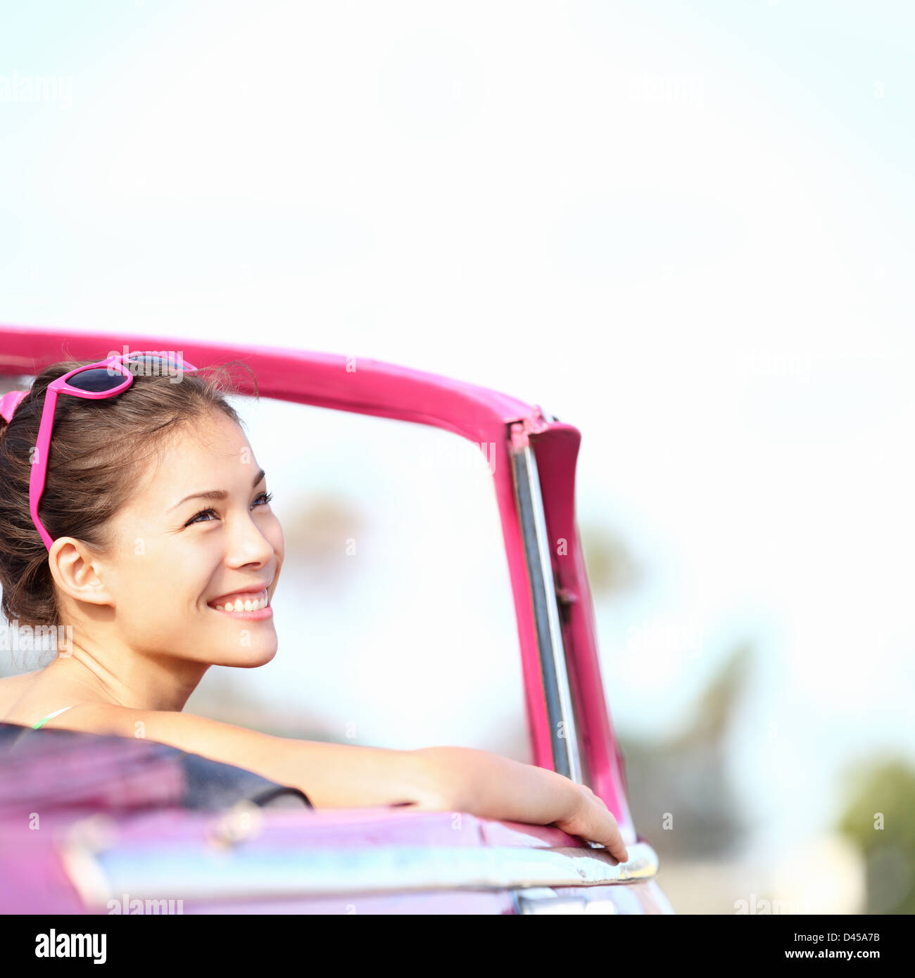 Giovane e bella multirazziale caucasico Cinese / donna asiatica in rosa vintage auto convertibili guardando al lato a spazio di copia Foto Stock