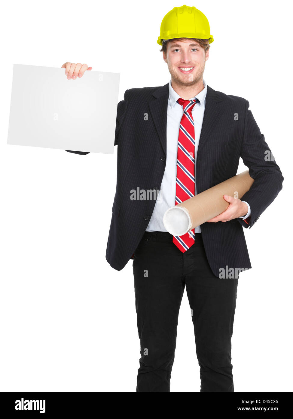 Giovani sorridenti caucasica ingegnere maschio / architetto mostra vuoto segno dei piani di contenimento e di indossare il casco giallo Foto Stock