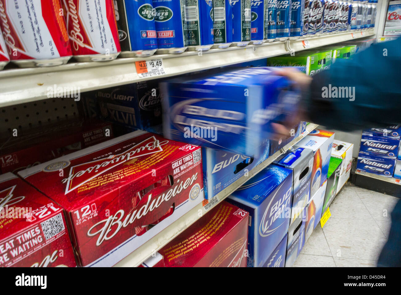 Una shopper afferra lattine di birra Budweiser dal birraio Anheuser Busch inBev in un supermercato a New York Foto Stock