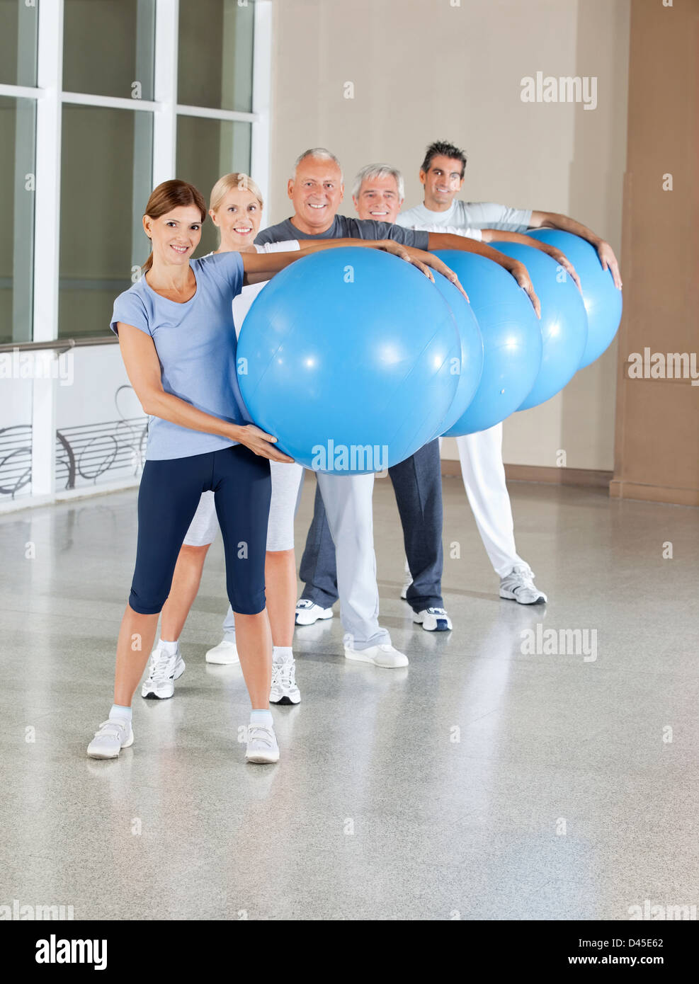 Senior di persone facendo formazione indietro con la palla nel centro fitness Foto Stock
