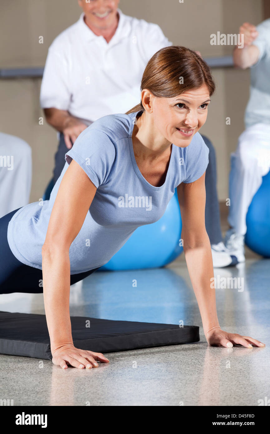 La donna nel centro fitness facendo premere up sul tappetino palestra Foto Stock