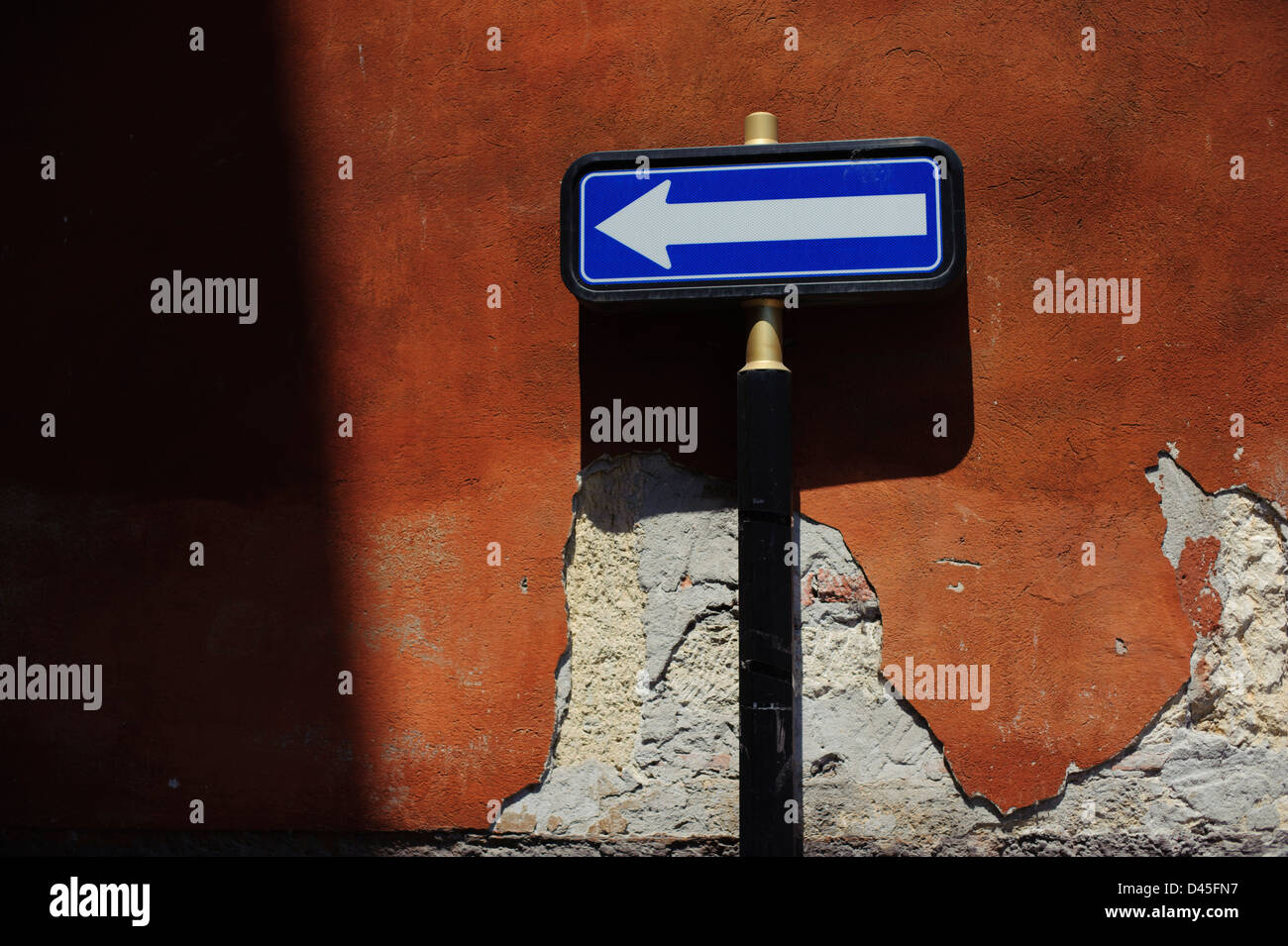 Blu e bianco segno di freccia contro un muro arancione, Verona, Italia. Foto Stock