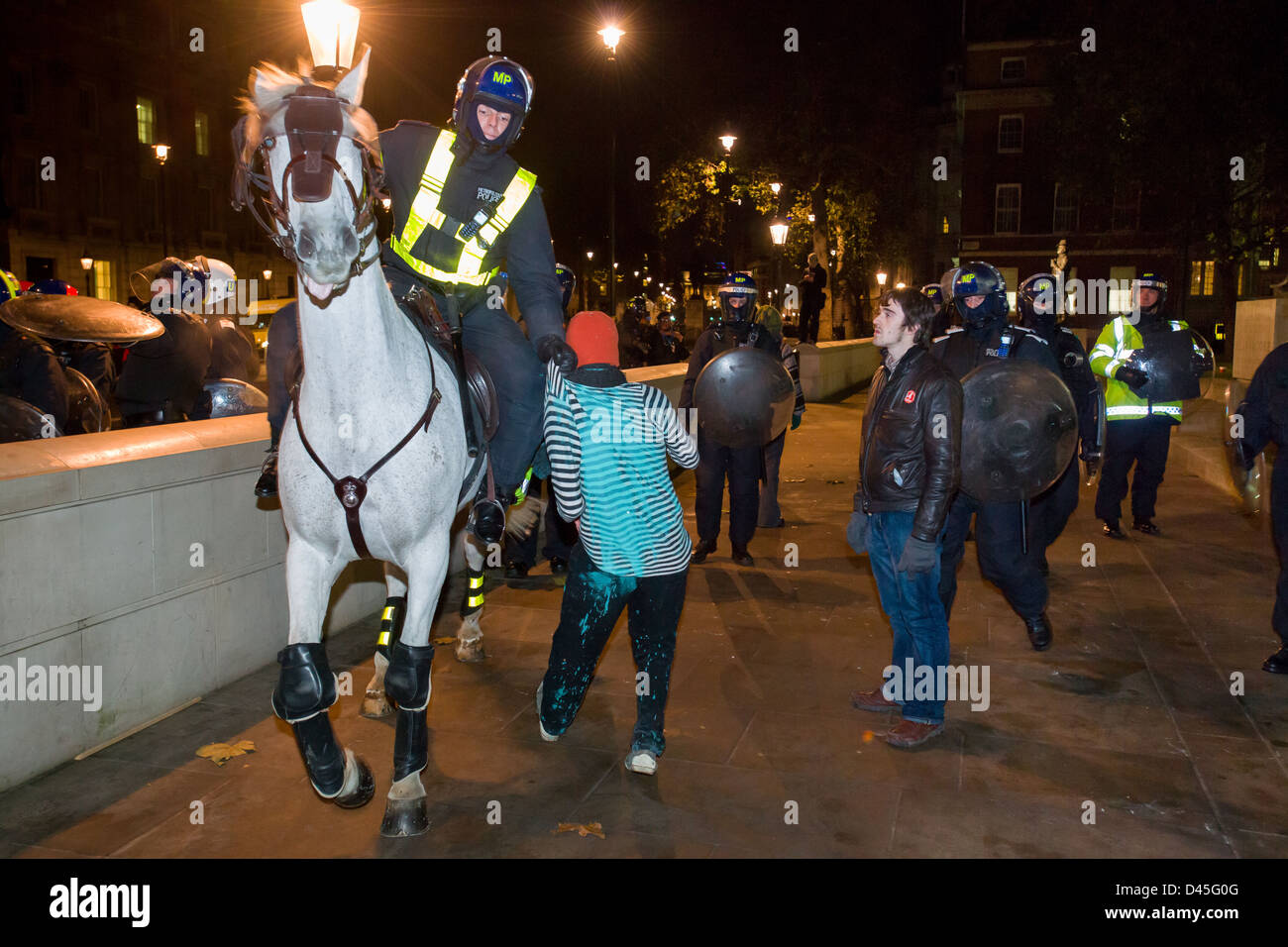 Montato un poliziotto in piena riot gear trascinando una protesta studente dai suoi vestiti su Whitehall di notte e giorno X3 manifestazione studentesca, Londra, Inghilterra Foto Stock