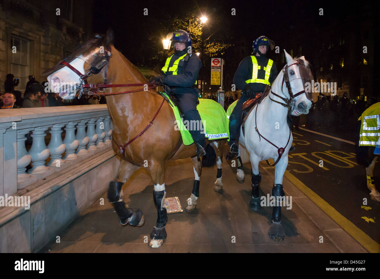 La polizia cavalli e cavalieri in piena sommossa marcia avanzando verso il basso Whitehall di notte e giorno X3 manifestazione studentesca, Londra, Inghilterra Foto Stock