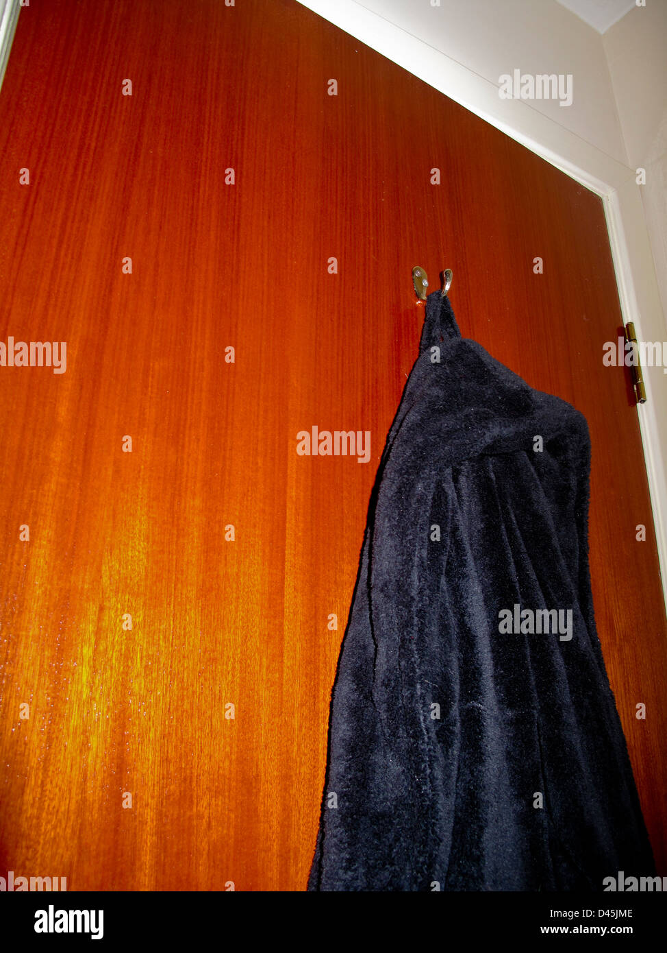 Asciugamani nero vestaglia appeso sul retro della porta della camera Foto Stock