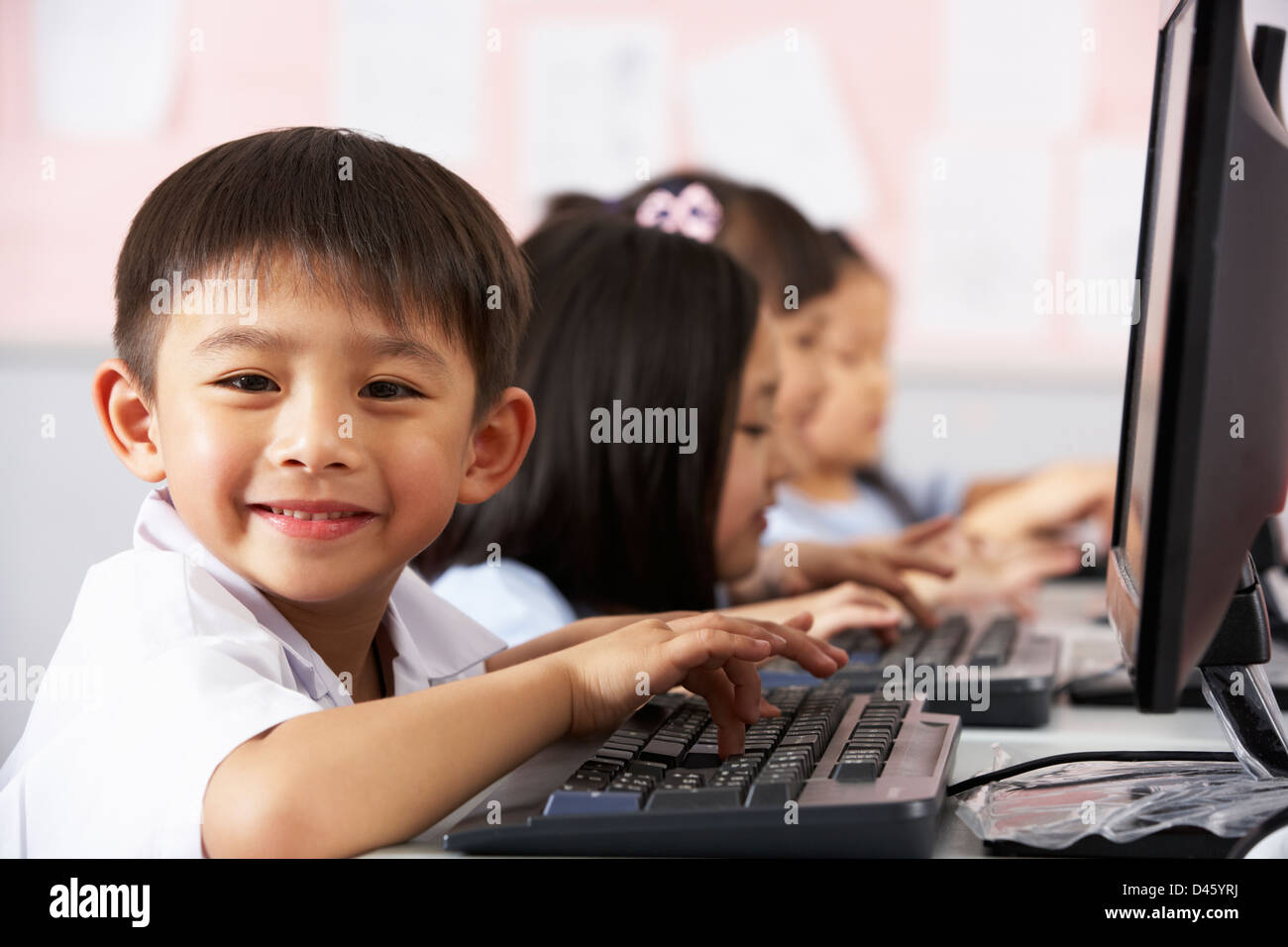 Pupilla d maschio utilizzando la tastiera durante la Classe Computer in cinese aula scolastica Foto Stock