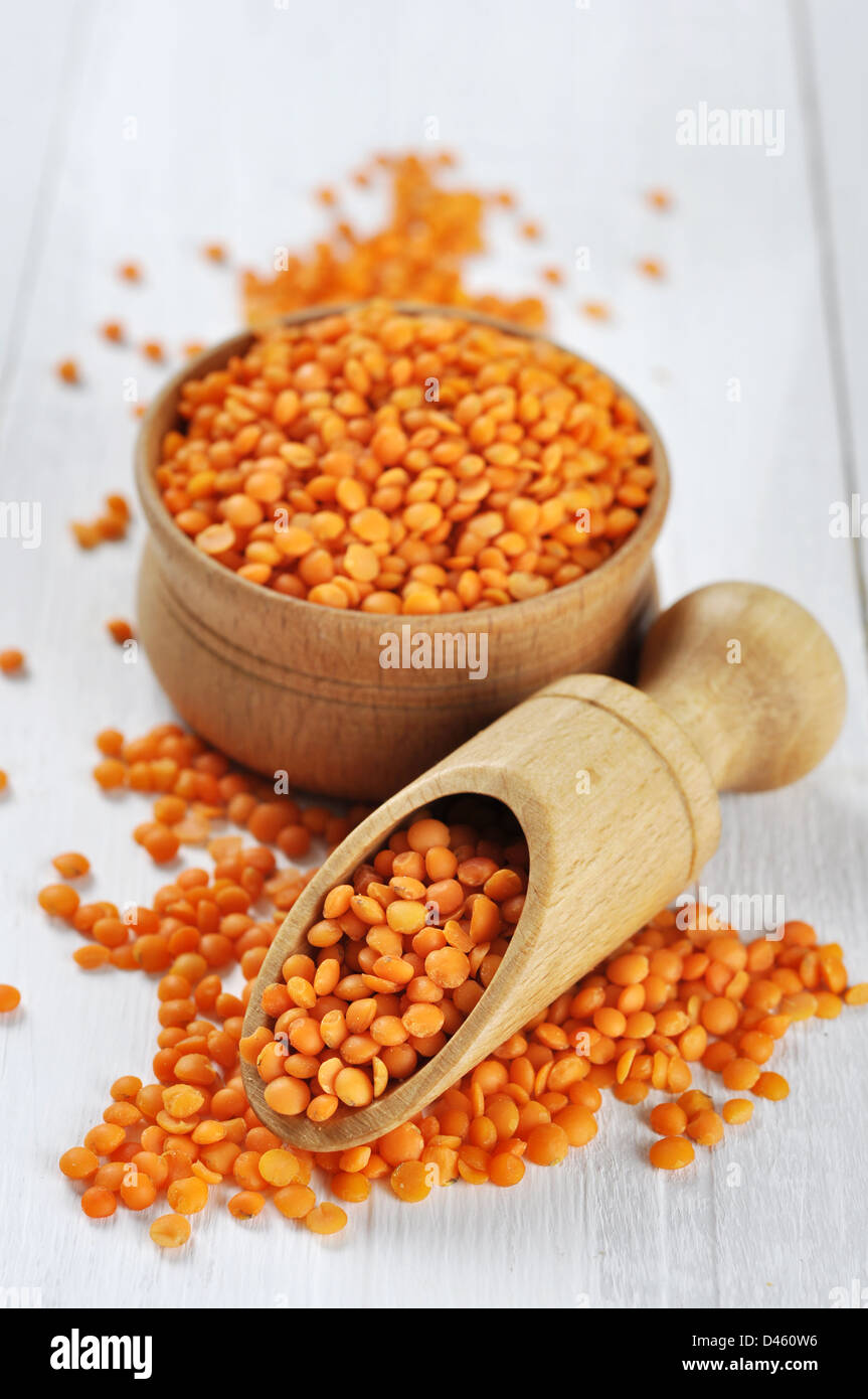 Rosso semi di lenticchie su un bianco sullo sfondo di legno Foto Stock