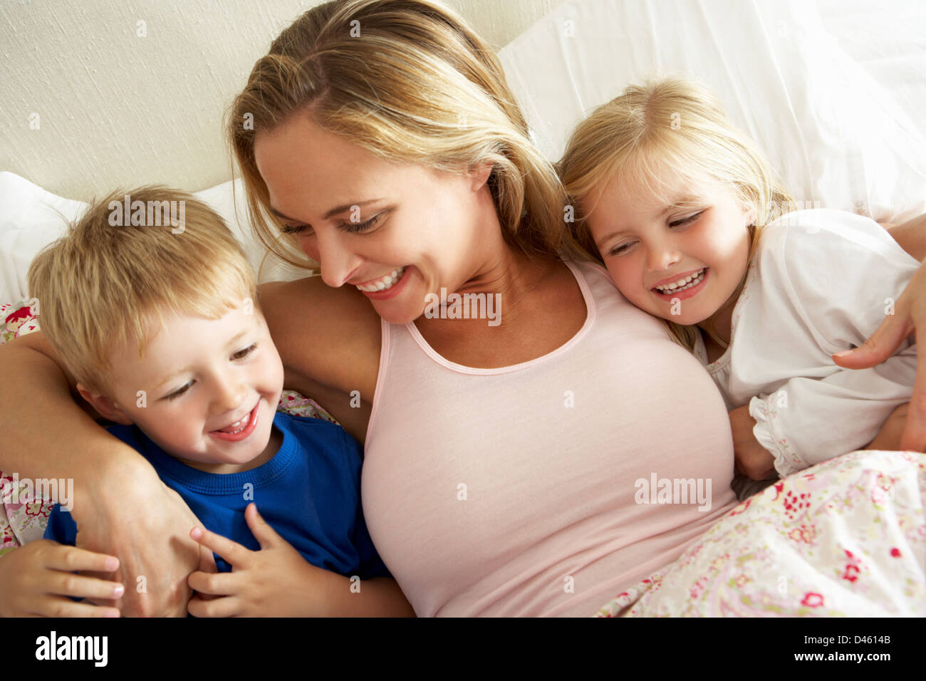 Madre e bambini rilassante insieme a letto Foto Stock