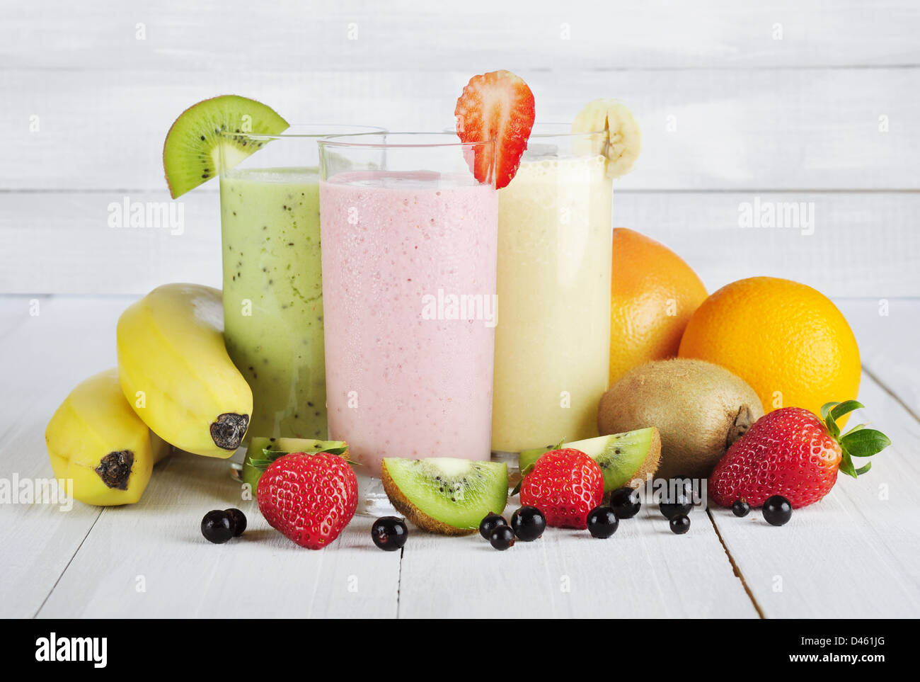 Frullati di frutta con ribes, confettura di fragole, kiwi, arancio e banana su bianco sullo sfondo di legno Foto Stock