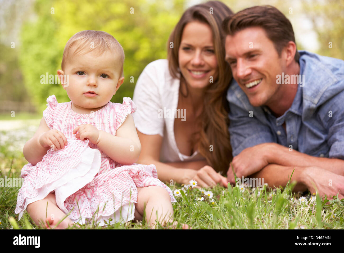 I genitori con bambino ragazza seduta nel campo di fiori d'estate Foto Stock