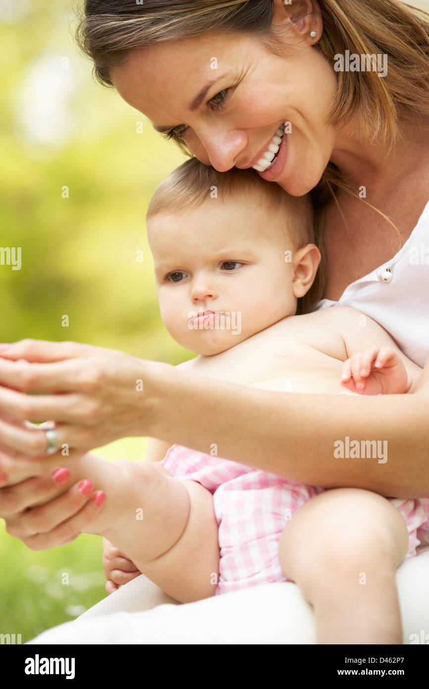 Madre seduta con Baby girl nel campo di fiori d'estate Foto Stock