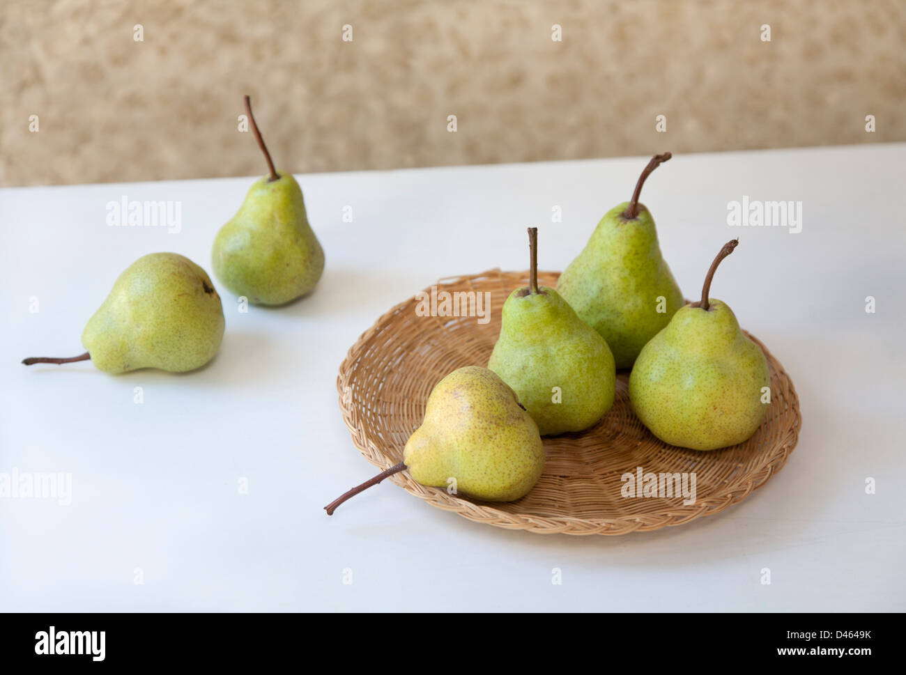 Sei pere verde su un tessuto piatto rattan set su un tavolo bianco superiore con un background modellato Foto Stock