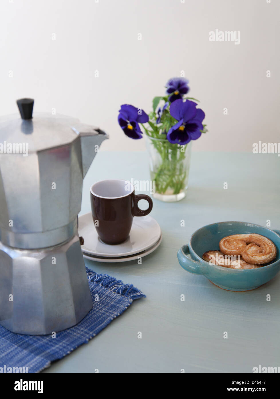 Tempo di pausa con un fornello caffettiera,tazzina, forma di cuore la pasticceria e un vaso di fiori Foto Stock
