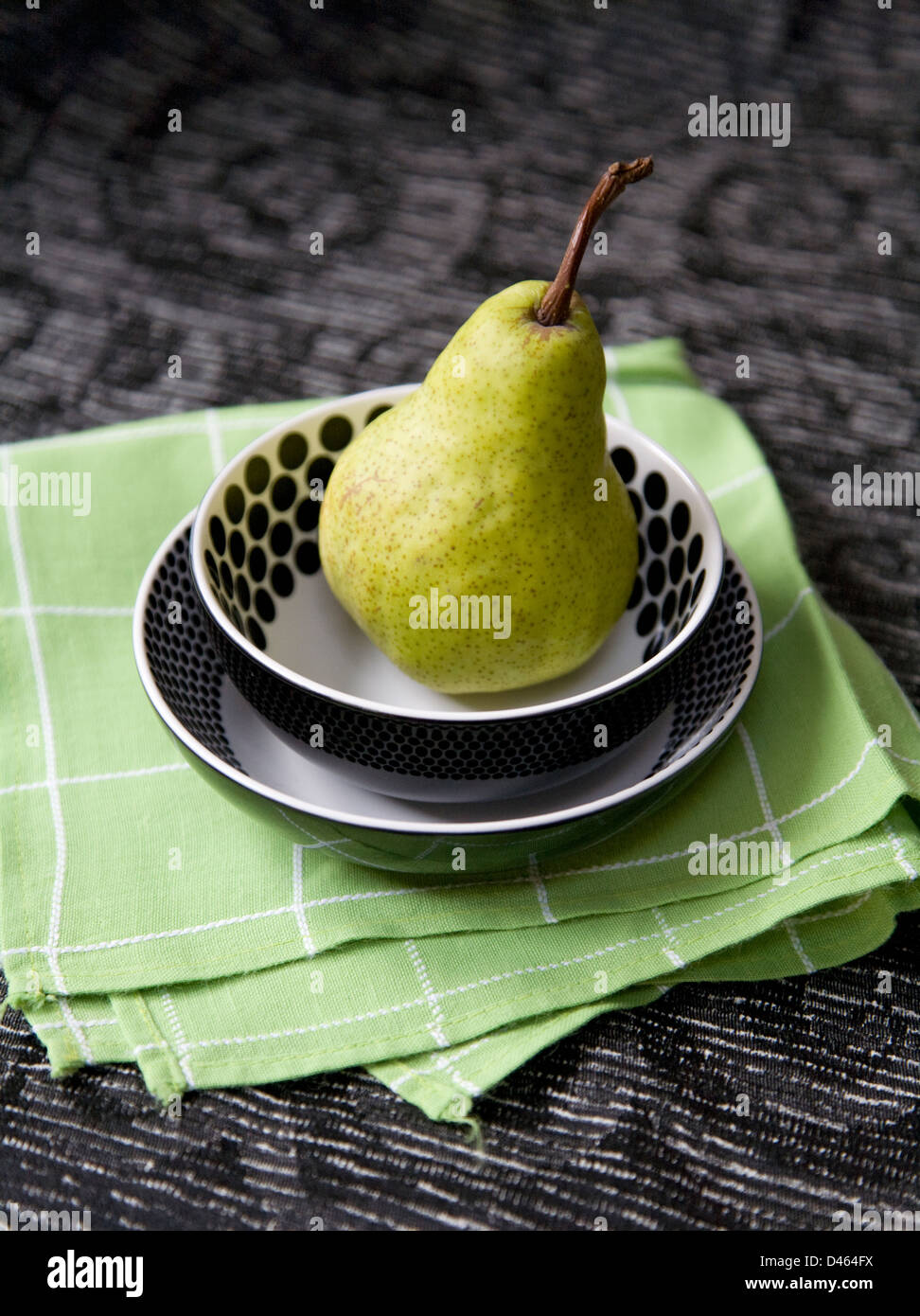 Una pera in due impilate a macchie piatti su un tovagliolo verde e nero modellato panno della tabella Foto Stock