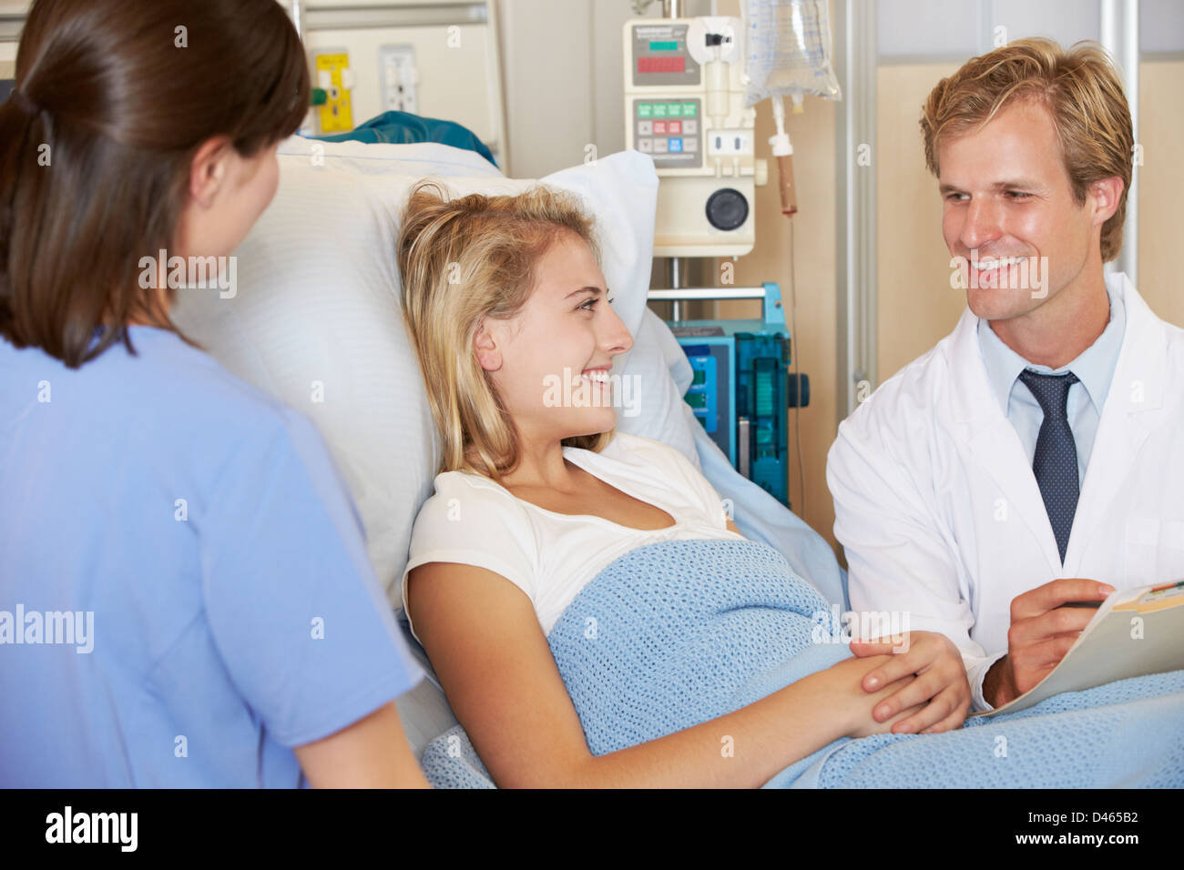 Medico con un infermiere parlando di adolescenti paziente femmina a letto Foto Stock