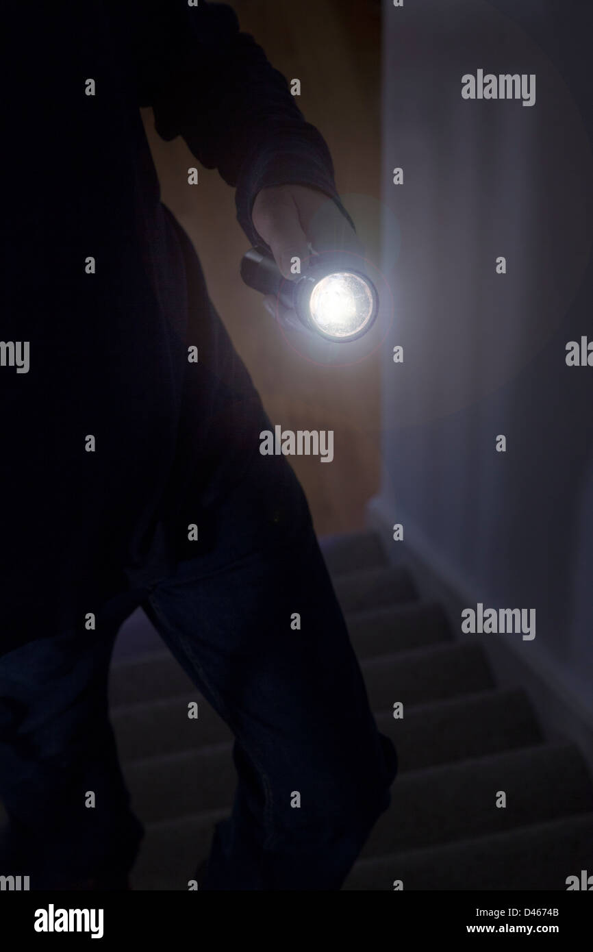 Ombroso intruso maschio tenendo un cannello o la luce del flash Foto Stock