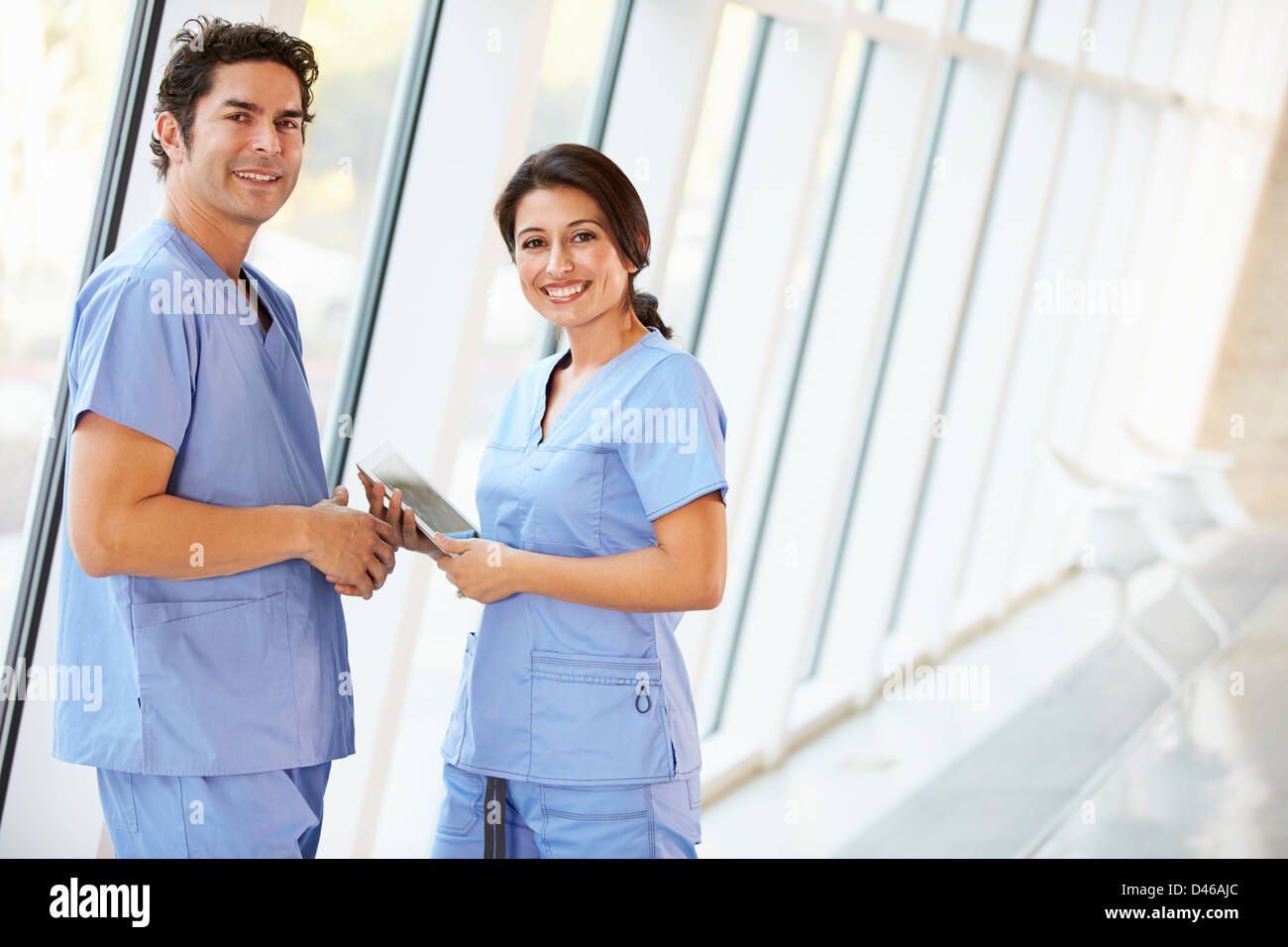 Il personale medico a parlare in ospedale corridoio con tavoletta digitale Foto Stock