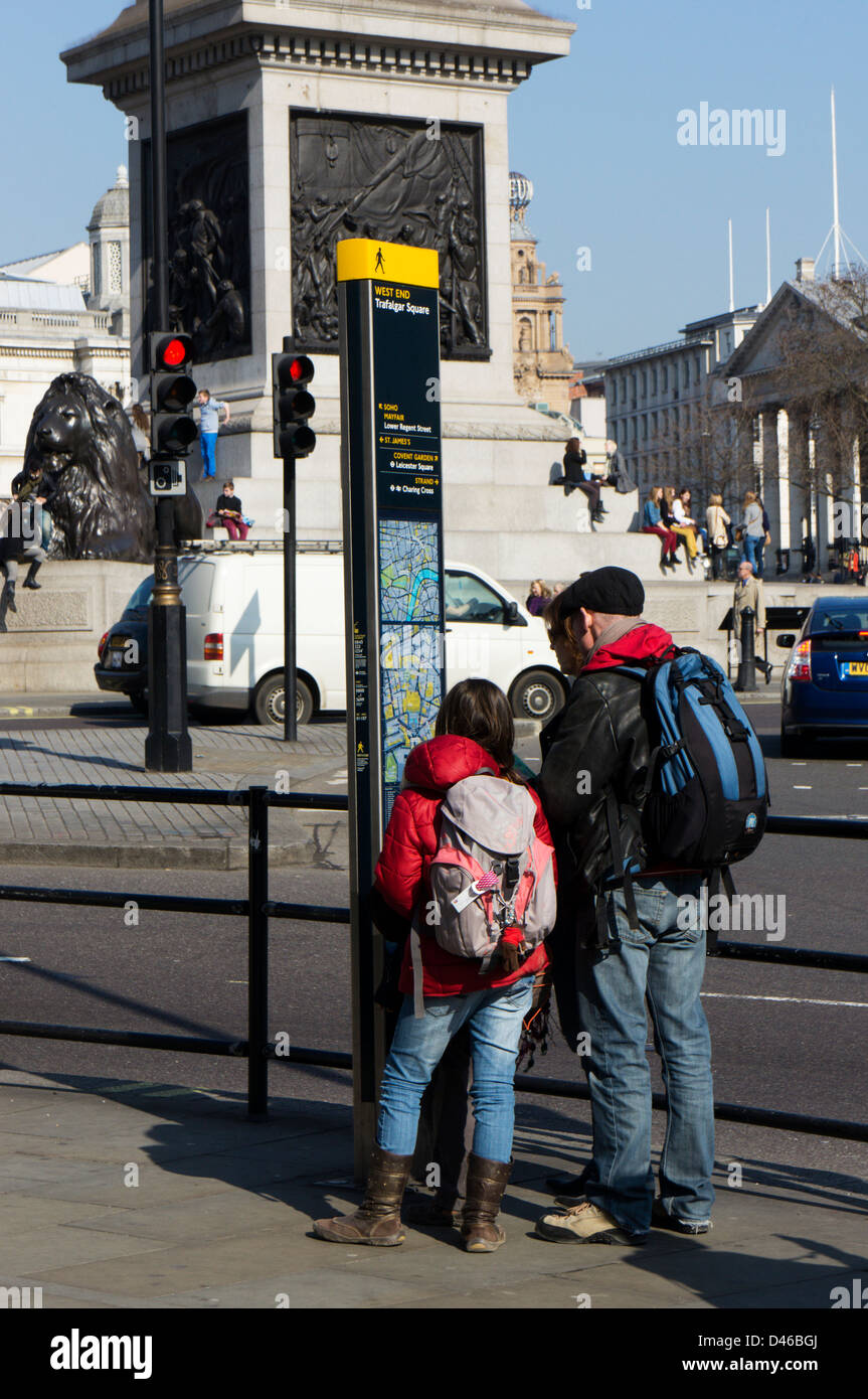 Una famiglia di consultare un cartello turistico e la mappa in Trafalgar Square. Foto Stock
