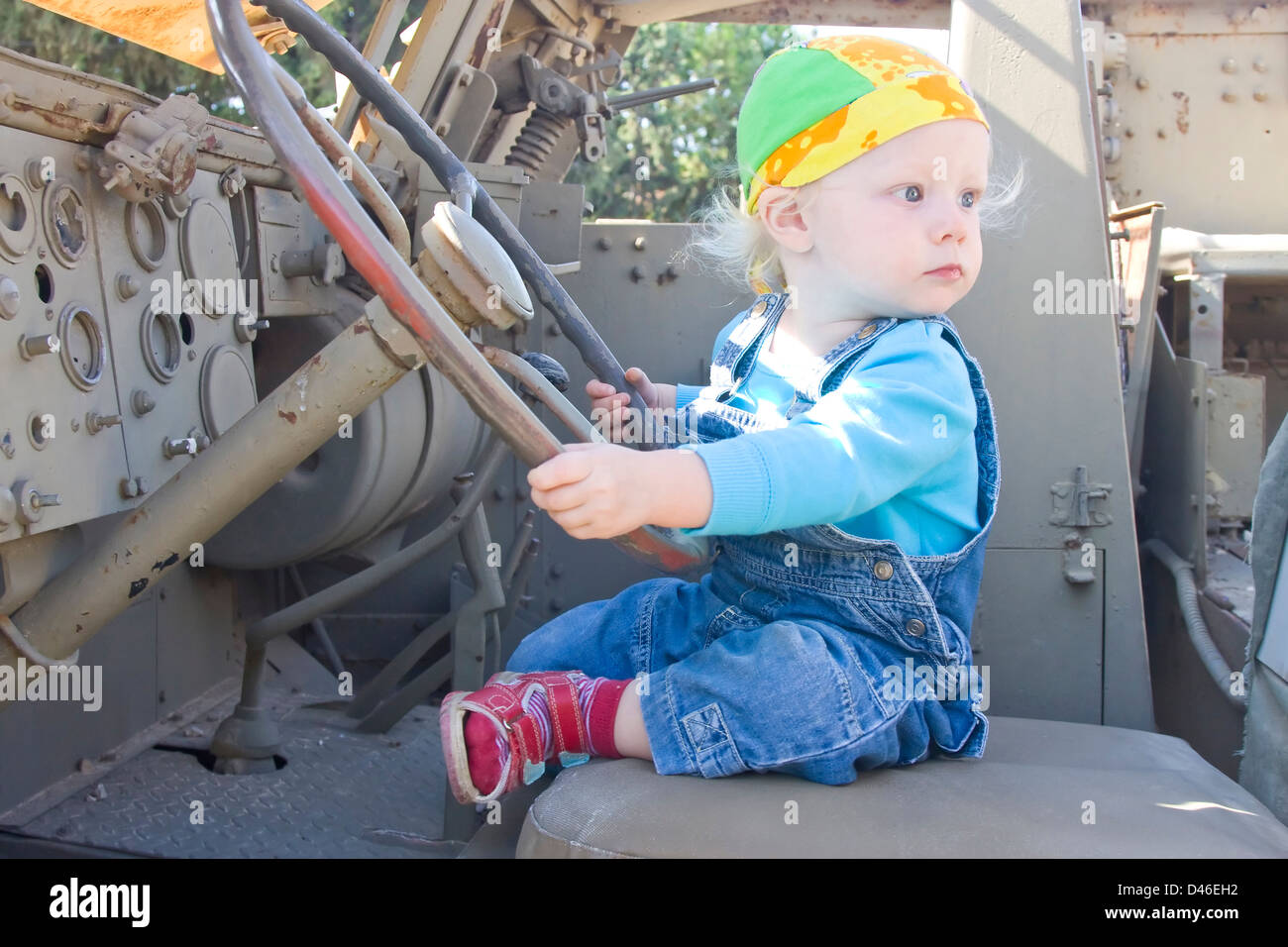 Baby girl guardando indietro durante la riproduzione con armor veicolo ruota motrice Foto Stock