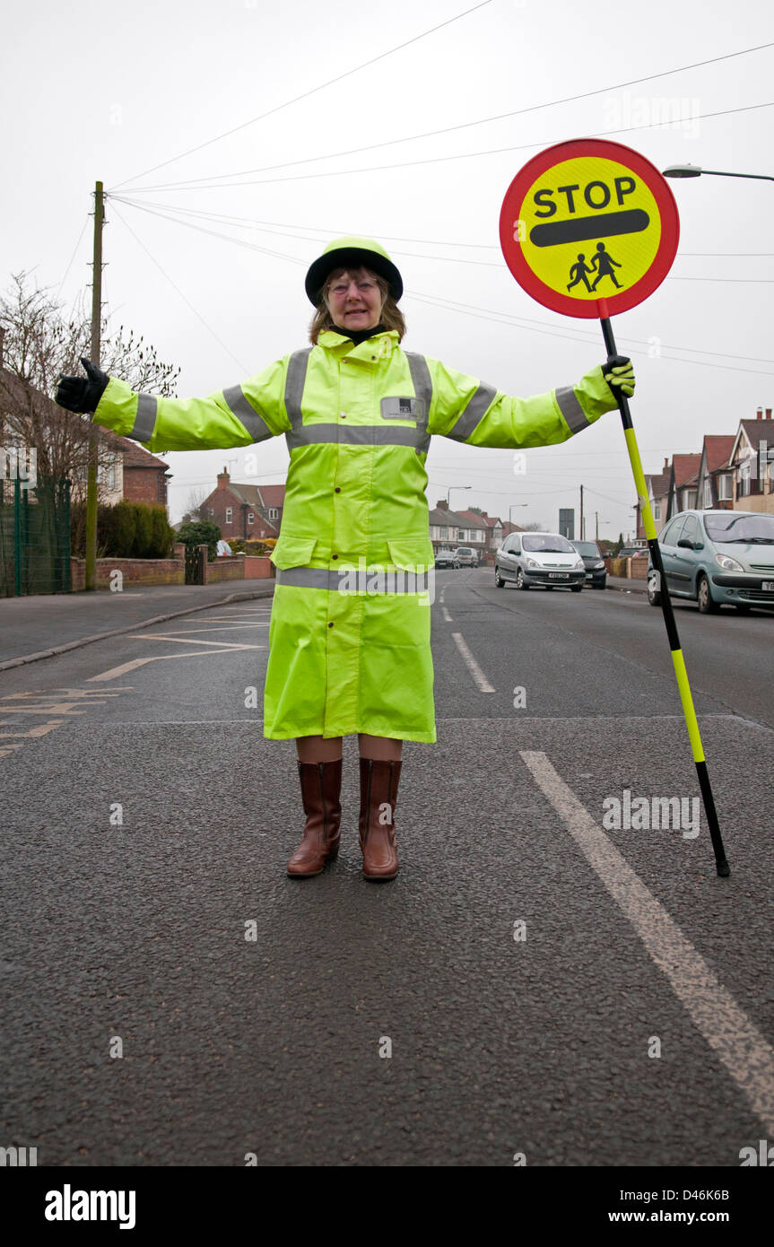 Un britannico lollipop lady o attraversamento di protezione del traffico di arresto al di fuori di una scuola per i bambini di attraversare la strada Foto Stock Un britannico lollipop lady o attraversamento di protezione del traffico di arresto al di fuori di una scuola per i bambini di attraversare la strada Foto Stock
