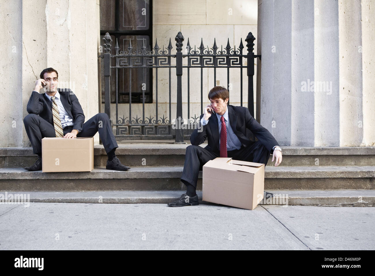 Due Wall street uomini licenziati, scatole di trasporto degli effetti personali dal lavoro. Foto Stock