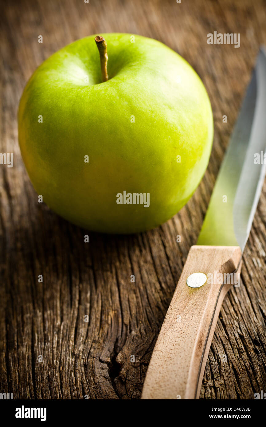 Mela verde con il coltello sul vecchio tavolo in legno Foto Stock