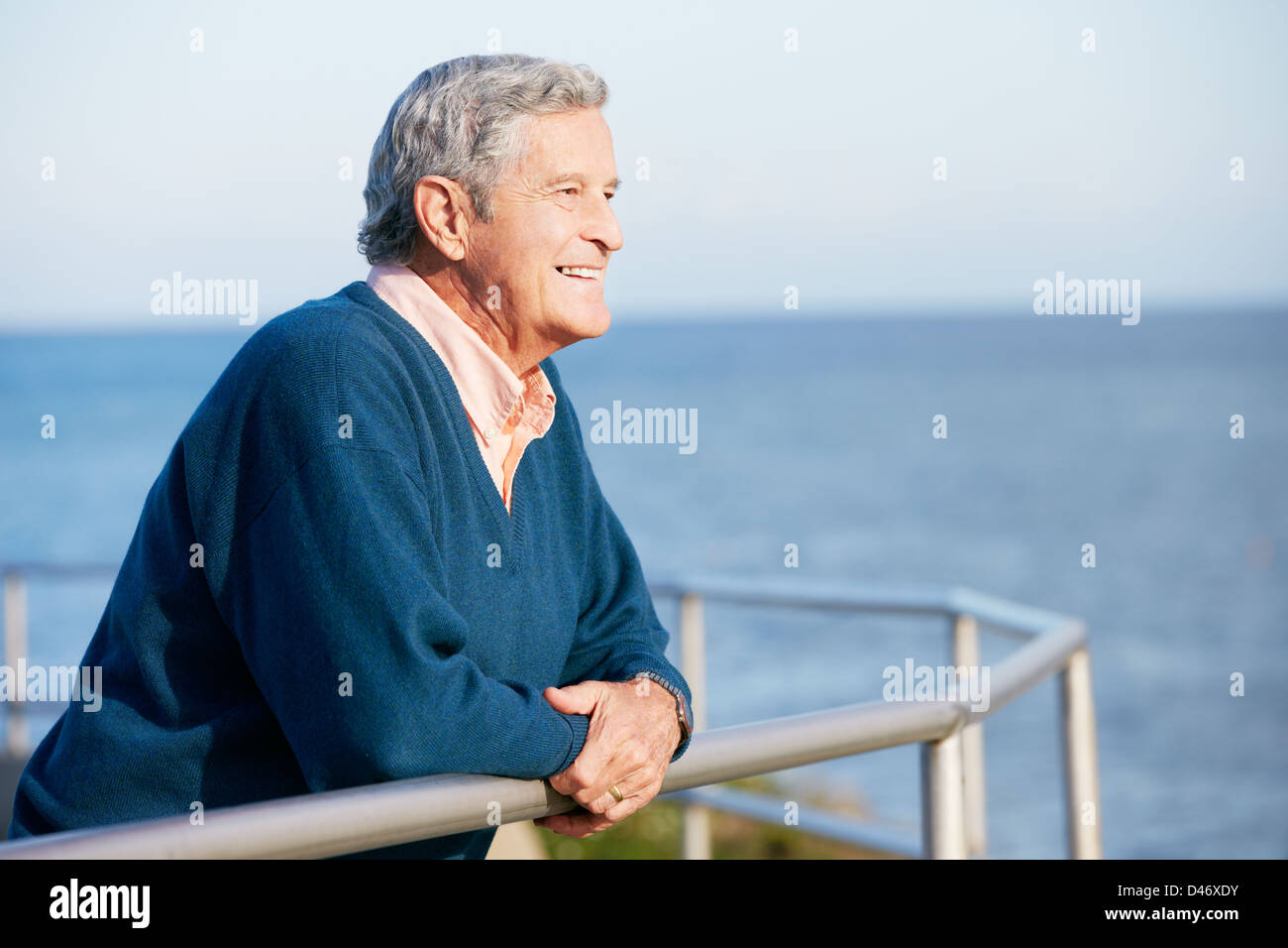 Senior Uomo cerca su parapetto in mare Foto Stock