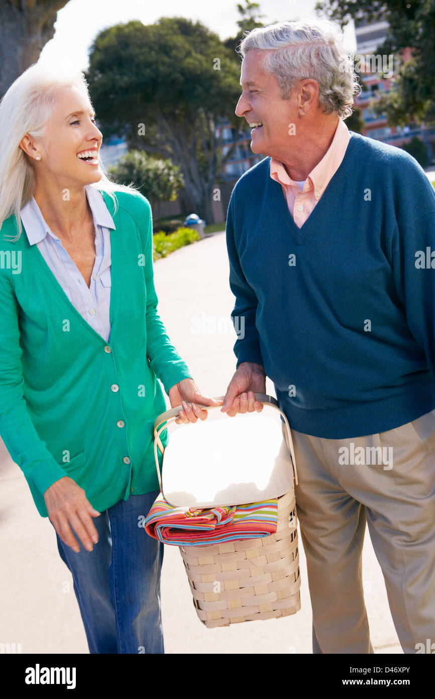 Coppia senior passeggiate nel parco insieme con cesto per pic-nic Foto Stock
