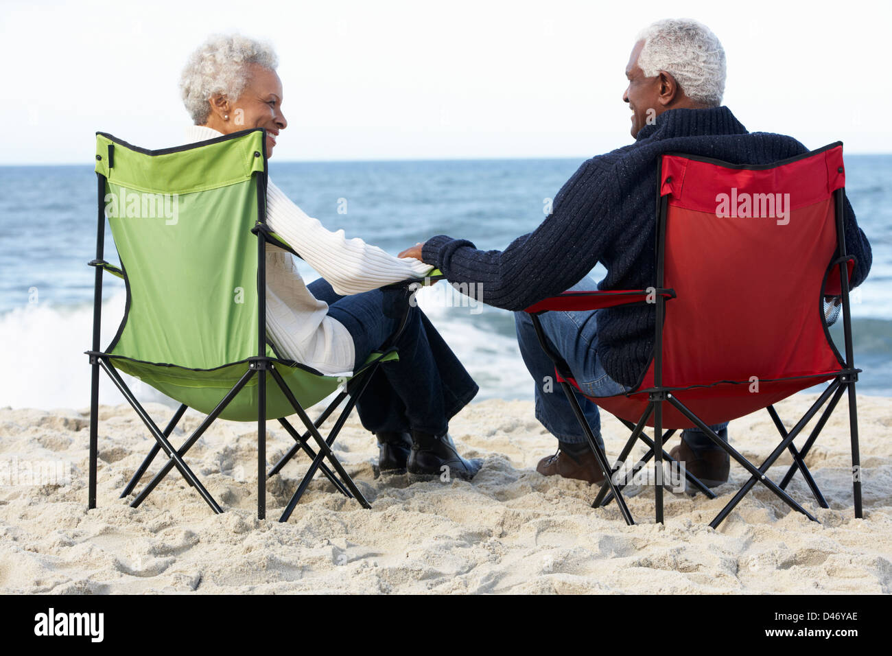 Coppia senior seduto sulla spiaggia in sedie a sdraio Foto Stock