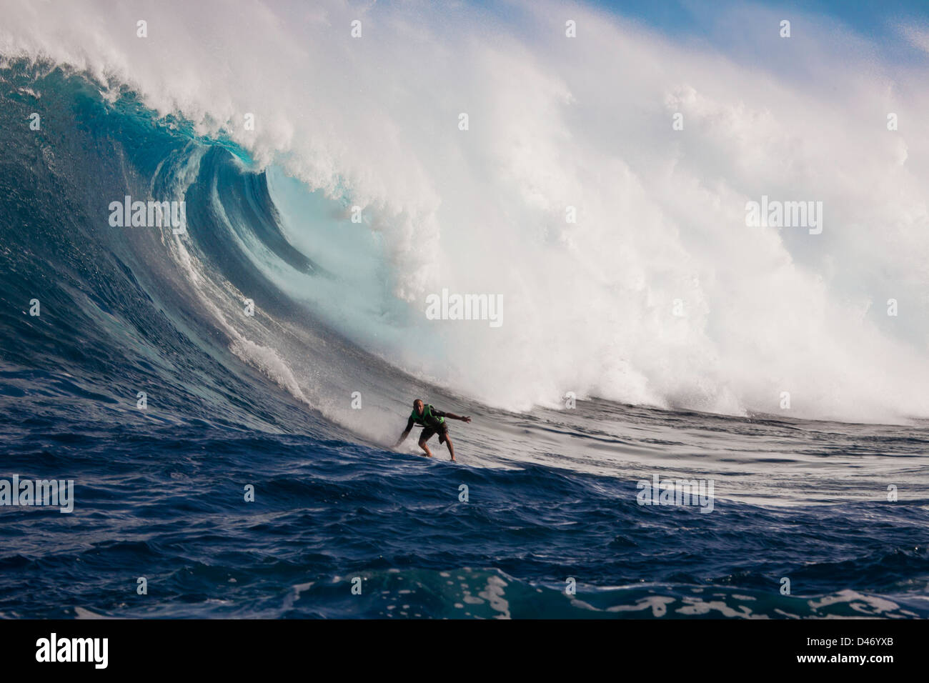 Un tow-in surfer scende giù per la faccia di Hawaii's big surf a Peahi (ganasce) off Maui, Hawaii, Stati Uniti d'America. Foto Stock