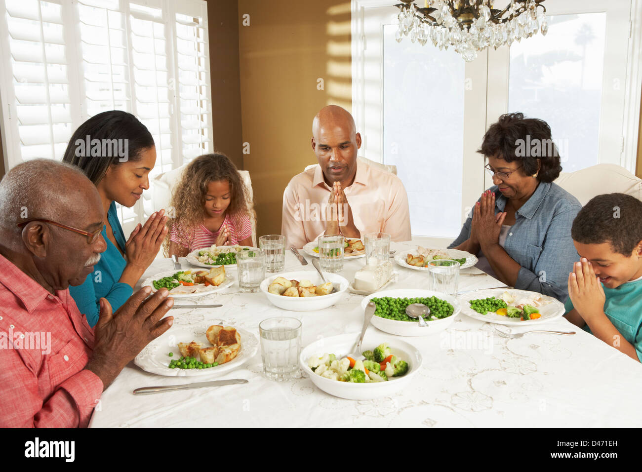 Generazione Multi Family dicendo grazia prima di pasto a casa Foto Stock