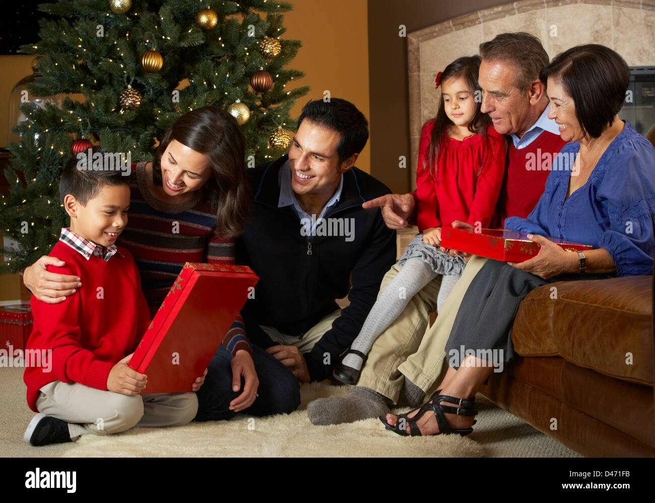 Multi generazione apertura famiglia Regali di natale nella parte anteriore della struttura ad albero Foto Stock