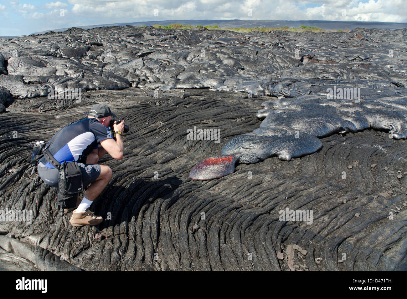 Un fotografo (MR) la ripresa di un nuovo movimento lento, flusso di lava pahoehoe da Kilauea, Big Island delle Hawaii. Foto Stock